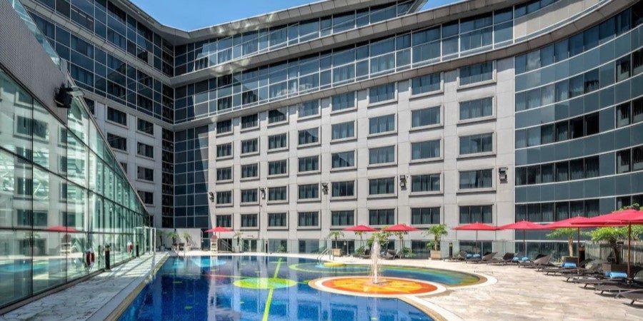 A serene hotel pool located in front of a contemporary building, inviting guests to relax and enjoy the surroundings.